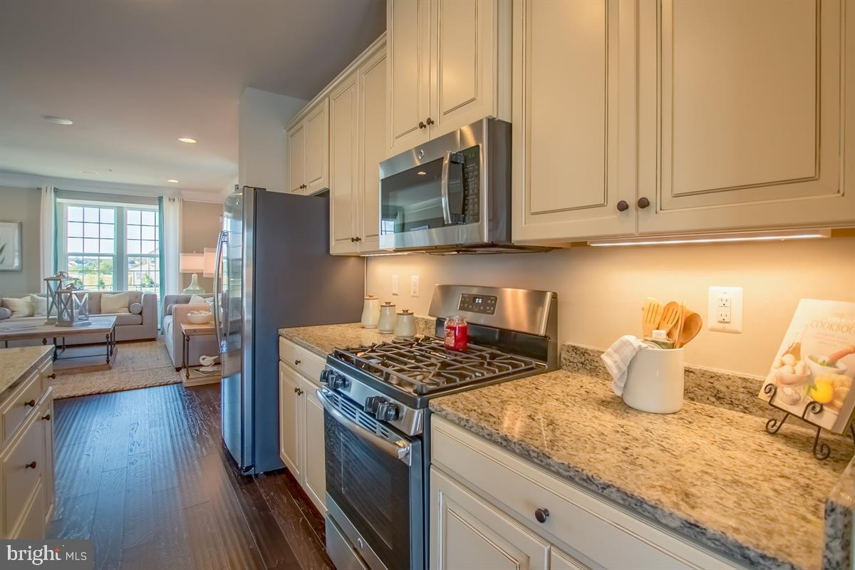7917 Gladden Farm Way Hanover, MD 21076 - Photo 3 of 27 a kitchen with stainless steel appliances granite countertop a stove a sink dishwasher and a microwave with wooden floor