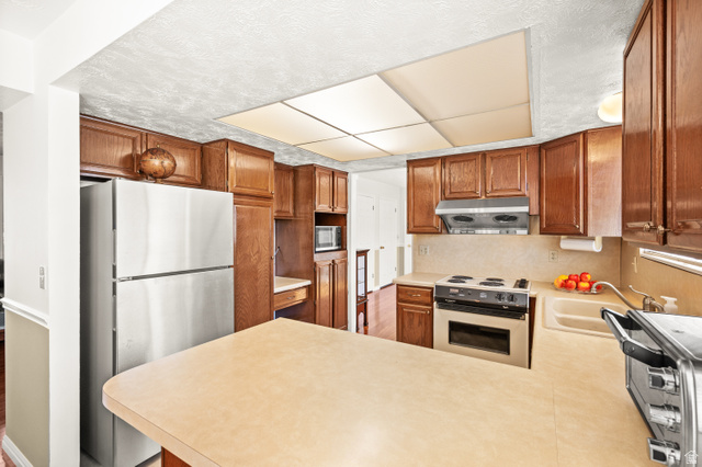 1650 Nichole Circle Sandy, UT 84093 - Photo 7 of 31 Kitchen featuring wood cabinetry, light-toned countertops, a built-in electric range, a stainless steel refrigerator, and a recessed ceiling light fixture
