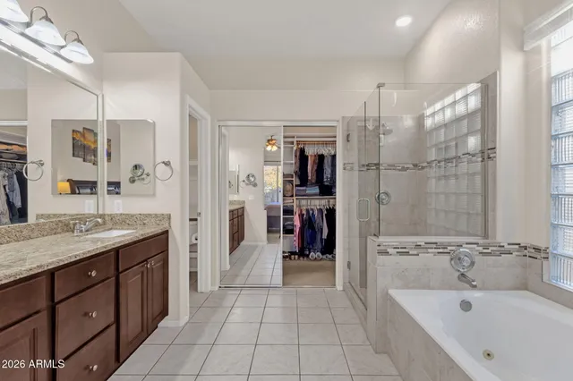 a spacious bathroom with a granite countertop sink a mirror a bathtub and shower