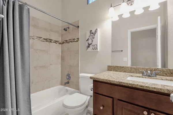 a bathroom with a granite countertop sink a toilet and shower