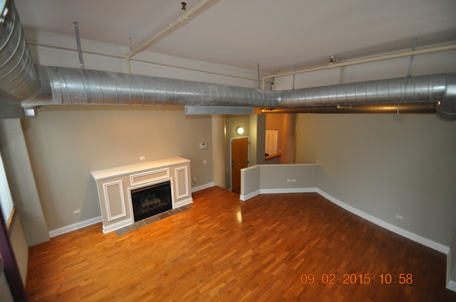 1727 South Indiana Avenue, Unit 26 Chicago, IL 60616 - Photo 4 of 10 a view of empty room with wooden floor and fireplace