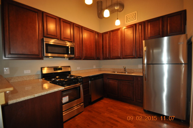 1727 South Indiana Avenue, Unit 26 Chicago, IL 60616 - Photo 6 of 10 a kitchen with granite countertop wooden cabinets a stove top oven and stainless steel appliances