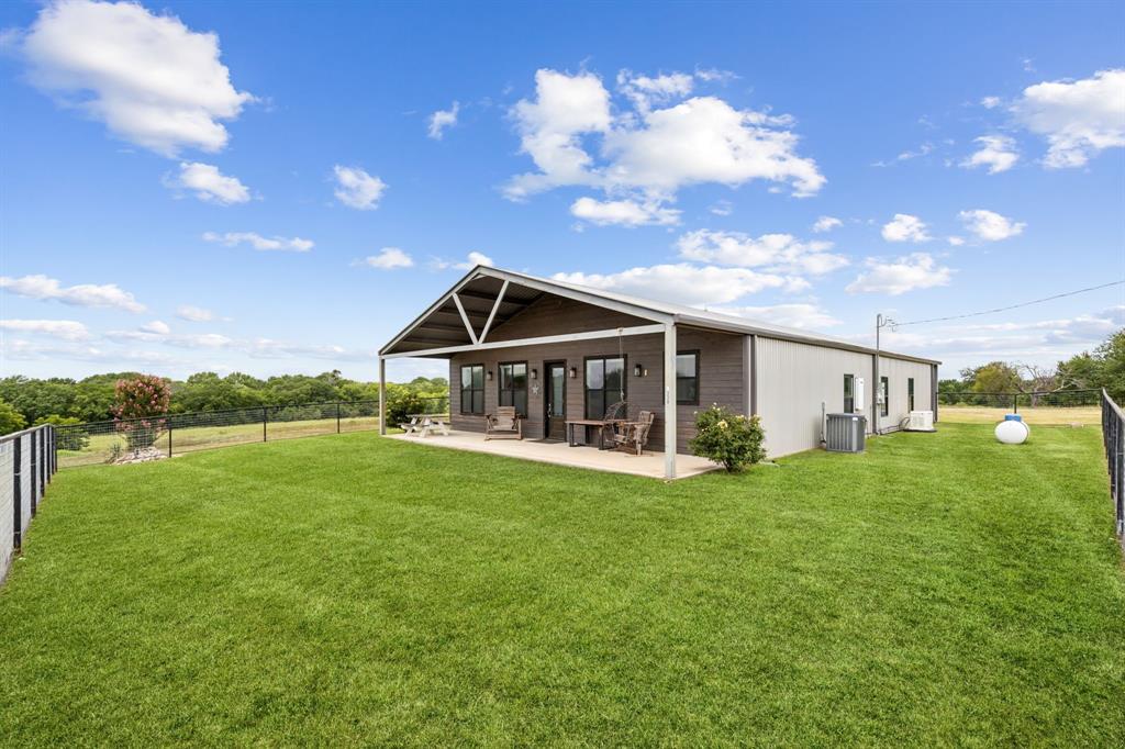 a front view of house with yard and trees in the background