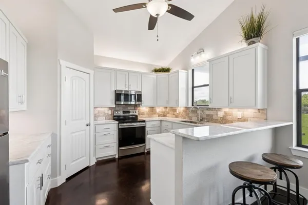 a kitchen with stainless steel appliances granite countertop a sink a stove a refrigerator cabinets and wooden floor