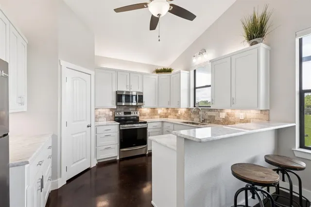 a kitchen with stainless steel appliances granite countertop a sink a stove a refrigerator cabinets and wooden floor