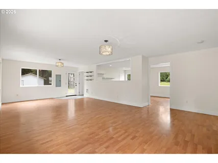 a view of an empty room with window and wooden floor
