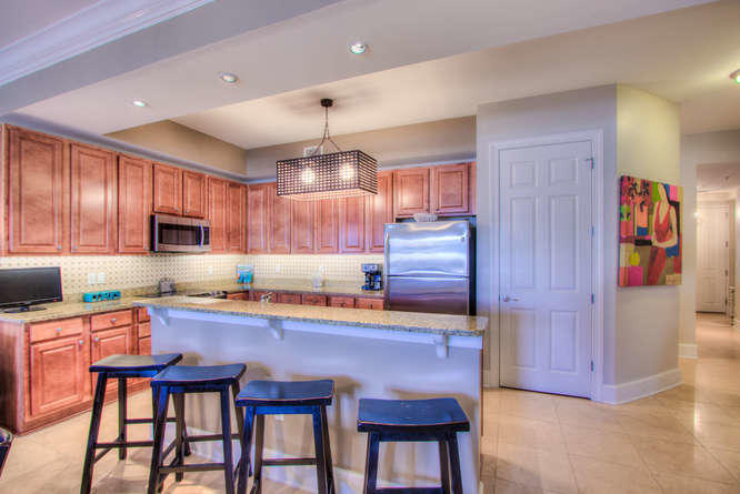 1653 West County Highway 30A, Unit 1116 Santa Rosa Beach, FL 32459 - Photo 7 of 41 a kitchen with granite countertop wooden cabinets and stainless steel appliances