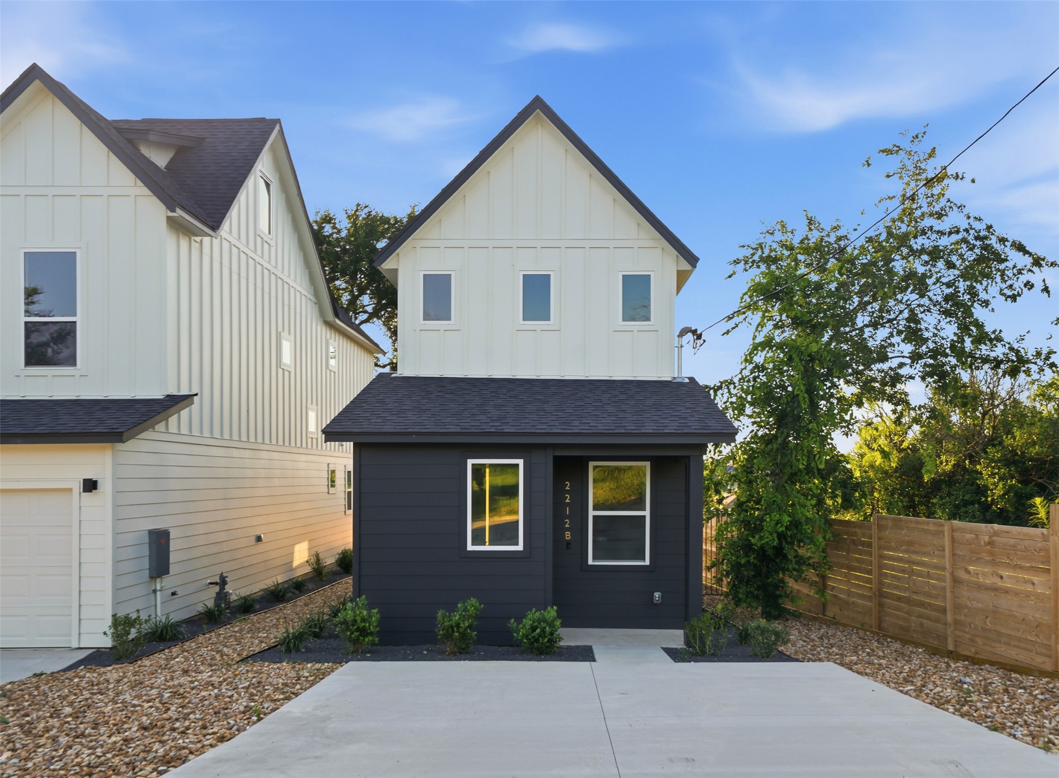 Modern two-story residence featuring a dark gray lower exterior and a light-toned upper exterior with a prominent gable roofline