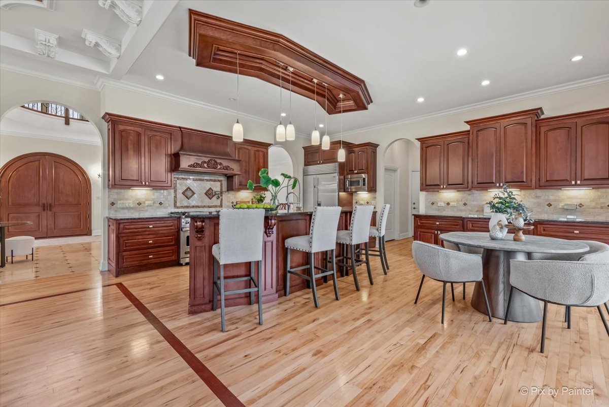 27 West Onwentsia Road Lake Forest, IL 60045 - Photo 21 of 73 a kitchen with stainless steel appliances granite countertop a stove top oven a refrigerator a dining table and chairs with wooden floor