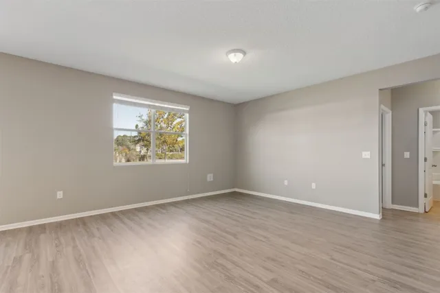 a view of an empty room with wooden floor and a window