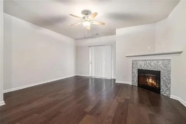 a view of an empty room with wooden floor fireplace and a window