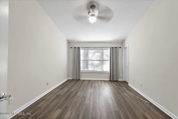 an empty room with wooden floor and windows