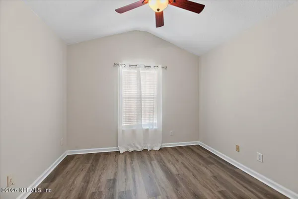 an empty room with wooden floor chandelier fan and windows