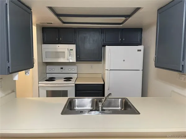 a kitchen with a refrigerator a stove a sink and white cabinets