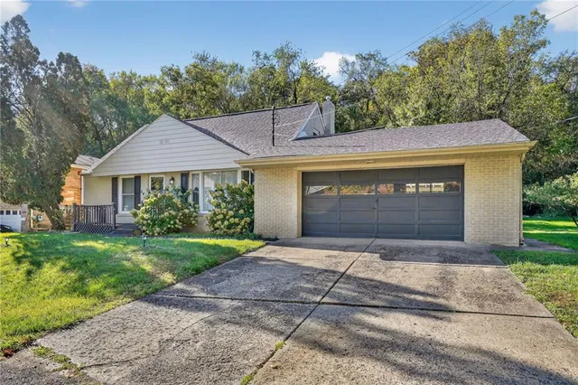 a front view of a house with a garden and trees