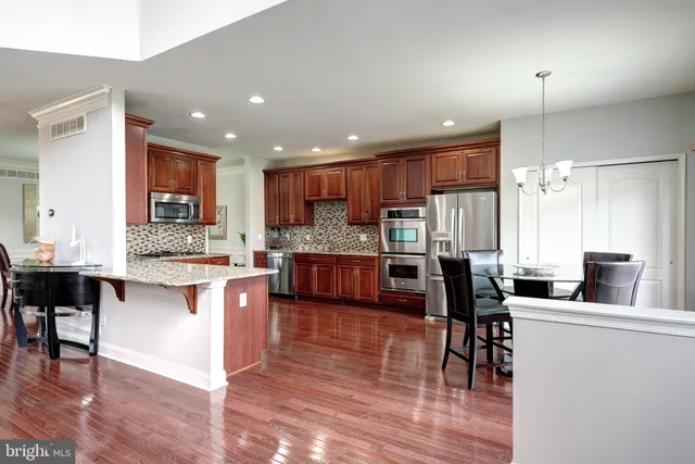 a kitchen with stainless steel appliances kitchen island granite countertop wooden floors and white cabinets