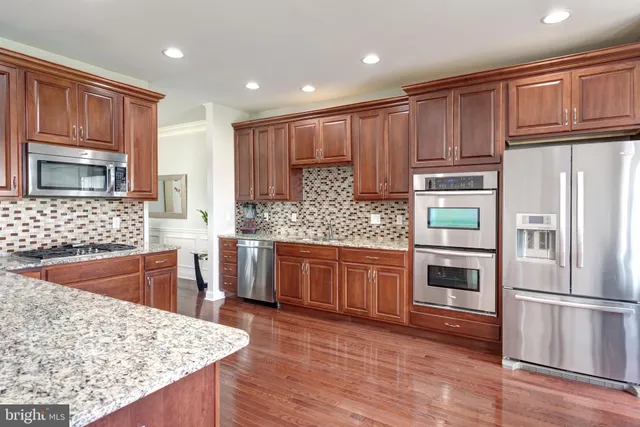 a kitchen with stainless steel appliances granite countertop a refrigerator stove top oven and sink