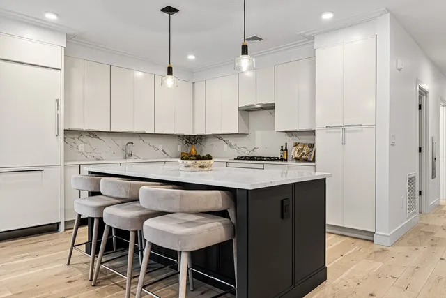 a kitchen with stainless steel appliances granite countertop a sink a stove a refrigerator and island with wooden floor