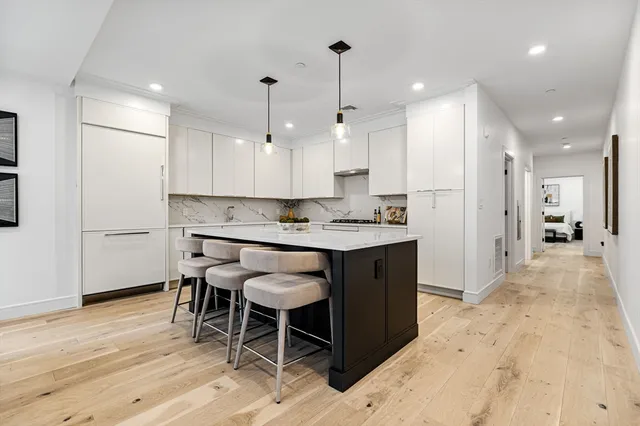 a large kitchen with stainless steel appliances kitchen island granite countertop a table chairs sink and cabinets