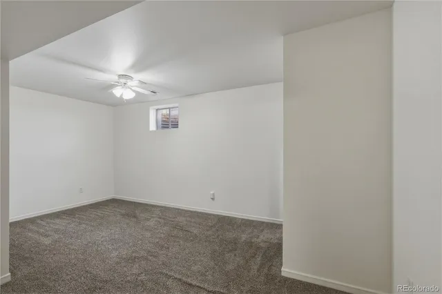 an empty room with a fan & a window