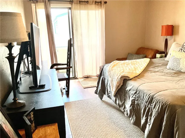 a bedroom with a bed and a flat tv screen on dresser
