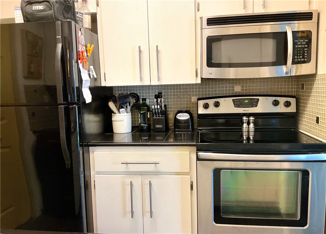 6718 Silvermine Drive, Unit 702 Austin, TX 78736 - Photo 8 of 19 a kitchen with stainless steel appliances kitchen island a stove and a microwave