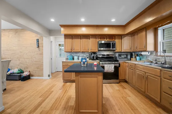 a kitchen with stainless steel appliances granite countertop a stove top oven a sink dishwasher and a refrigerator with wooden floor