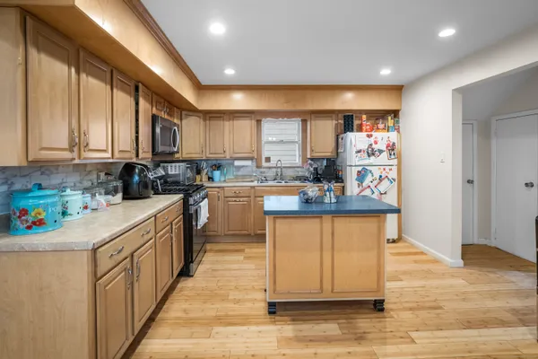 a kitchen with stainless steel appliances granite countertop a stove top oven a sink and a refrigerator