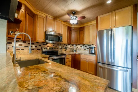 a kitchen with stainless steel appliances granite countertop a refrigerator stove and sink