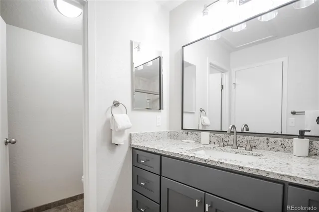 a bathroom with a granite countertop sink and a mirror