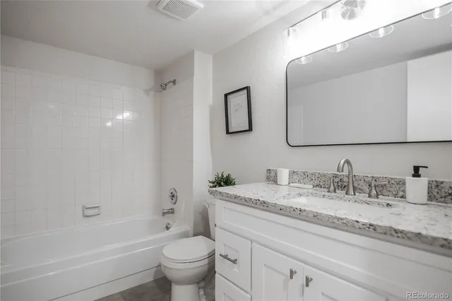 a bathroom with a granite countertop toilet sink and a mirror