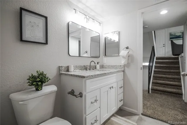 a bathroom with a granite countertop sink toilet and a mirror