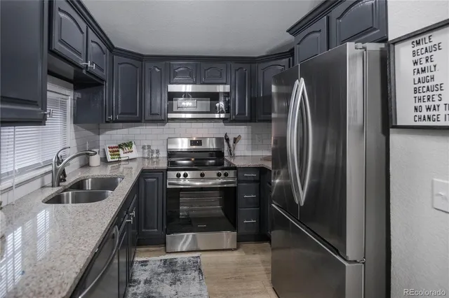 a kitchen with stainless steel appliances granite countertop a refrigerator a stove a sink and dishwasher