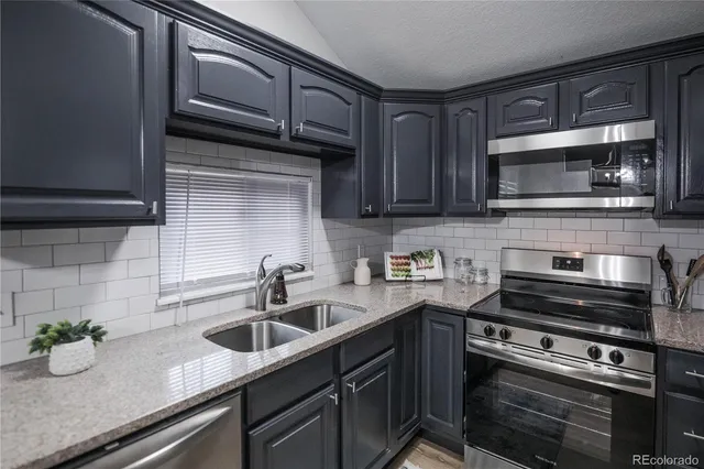 a kitchen with granite countertop a sink stainless steel appliances and cabinets