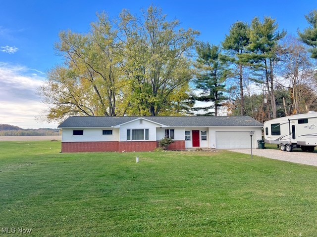 Single story home with a front lawn, driveway, an attached garage, and brick siding
