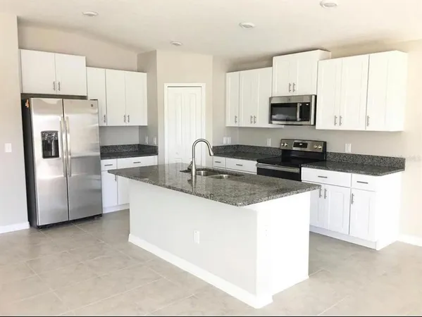 a kitchen with stainless steel appliances granite countertop a refrigerator a stove a sink and white cabinets