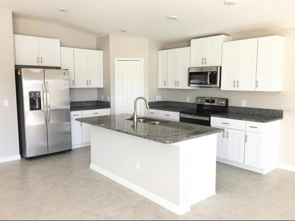 31699 Sun Kettle Loop Wesley Chapel, FL 33545 - Photo 3 of 18 a kitchen with stainless steel appliances granite countertop a refrigerator a stove a sink and white cabinets