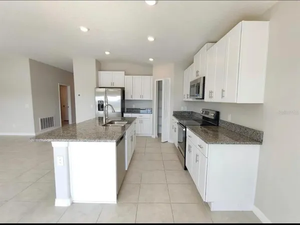 a large kitchen with stainless steel appliances granite countertop a stove a sink and a refrigerator