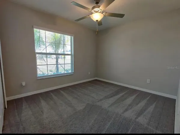 an empty room with a window and a fan