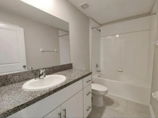 a bathroom with a granite countertop sink a toilet and shower