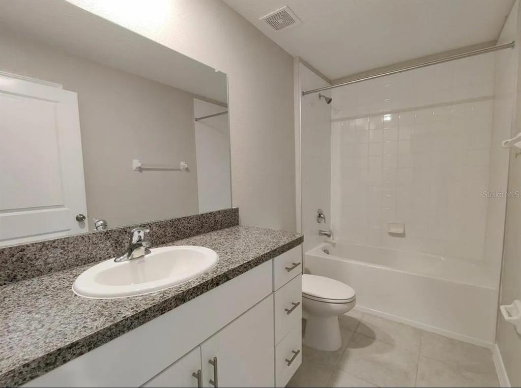 31699 Sun Kettle Loop Wesley Chapel, FL 33545 - Photo 10 of 18 a bathroom with a granite countertop sink a toilet and shower