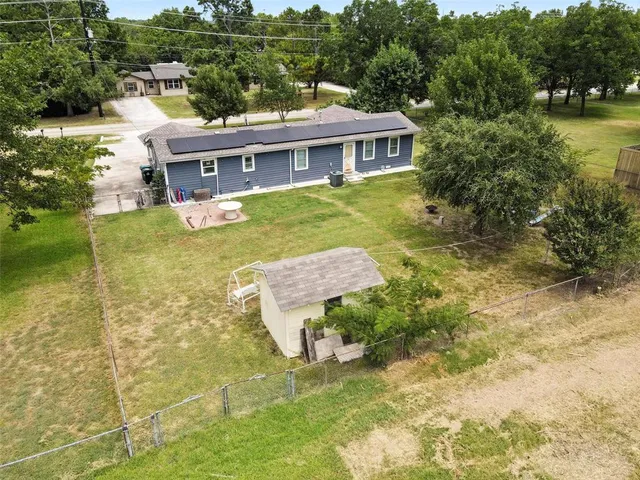 an aerial view of a house with swimming pool and large trees