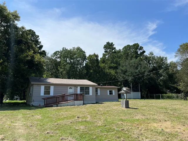 a house is sitting in middle of the green field