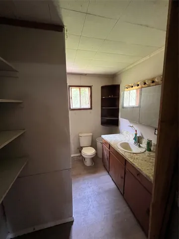 a spacious bathroom with a granite countertop sink a toilet and a blue tub