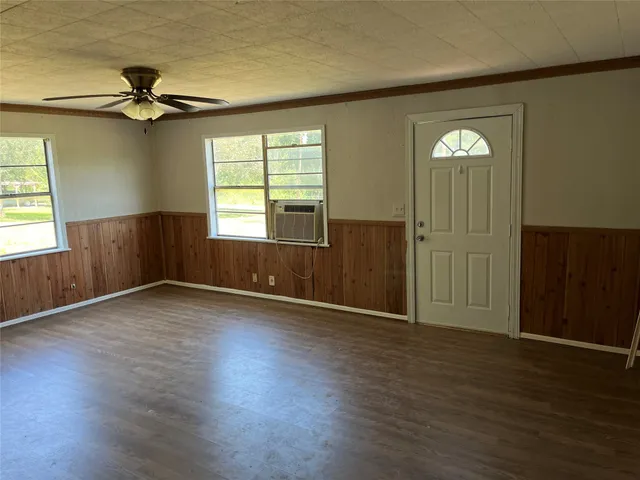 an empty room with wooden floor cabinet and windows