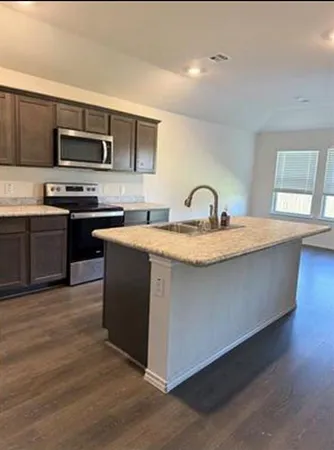 a kitchen with stainless steel appliances granite countertop a sink a stove top oven and wooden floors