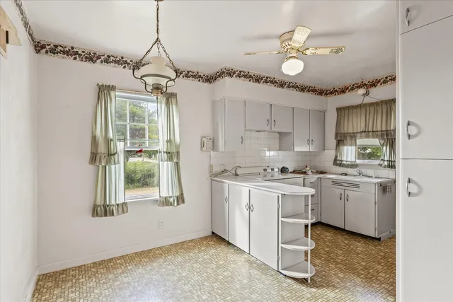 a kitchen that has a lot of white cabinets and stainless steel appliances
