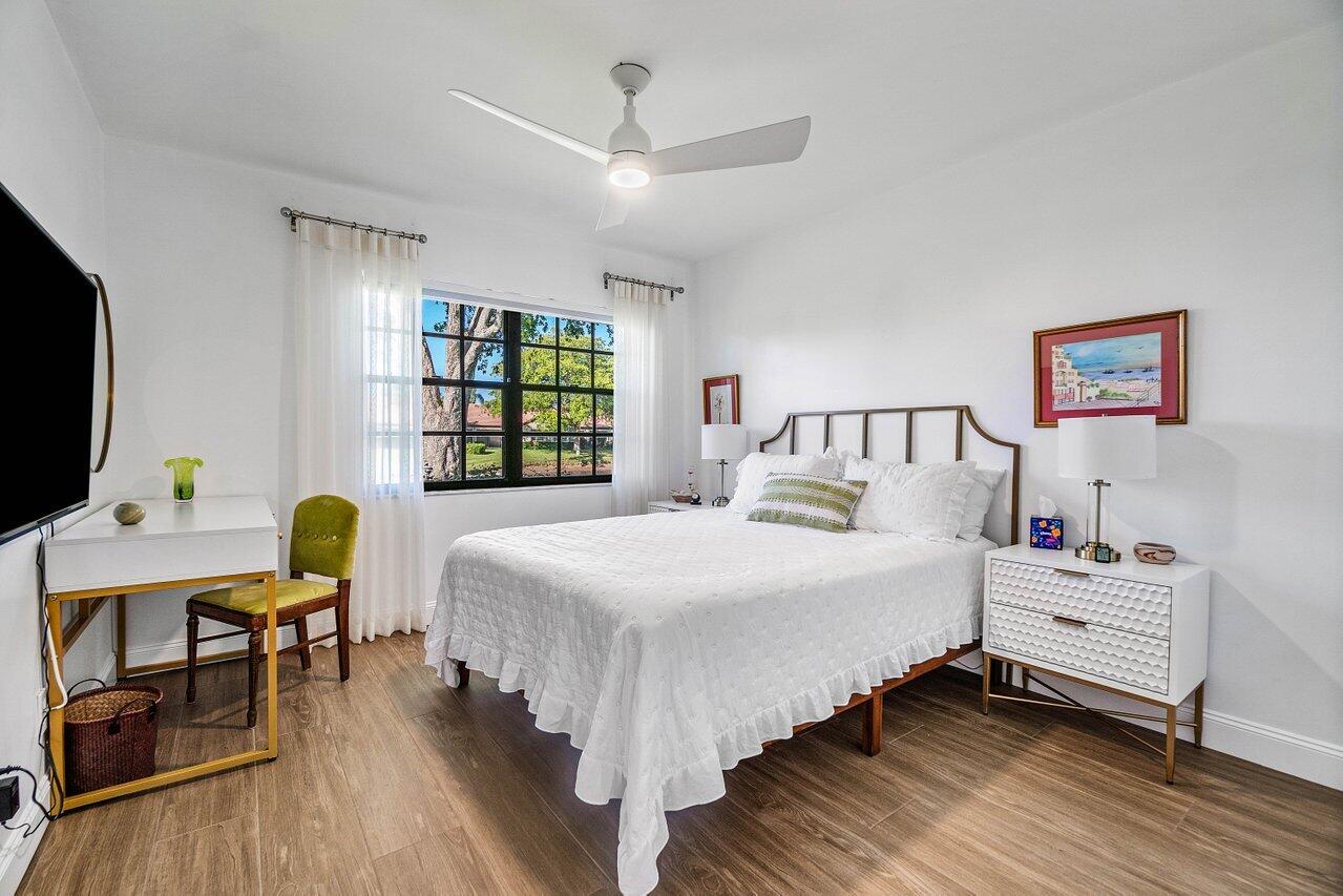 8195 Mooring Circle Boynton Beach, FL 33472 - Photo 16 of 28 a bedroom with a bed a desk and chair with wooden floor