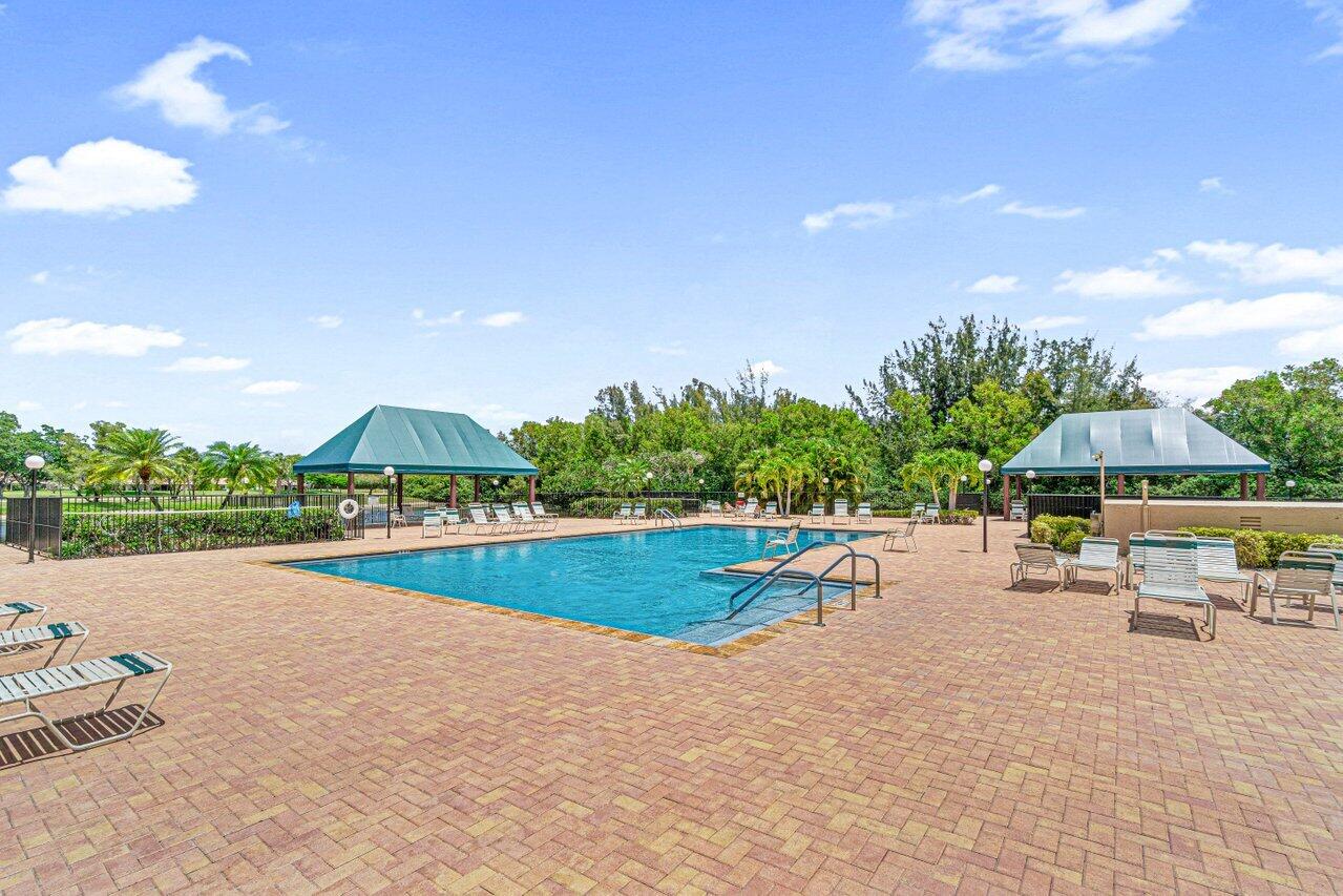8195 Mooring Circle Boynton Beach, FL 33472 - Photo 25 of 28 a view of a swimming pool with lawn chairs under an umbrella