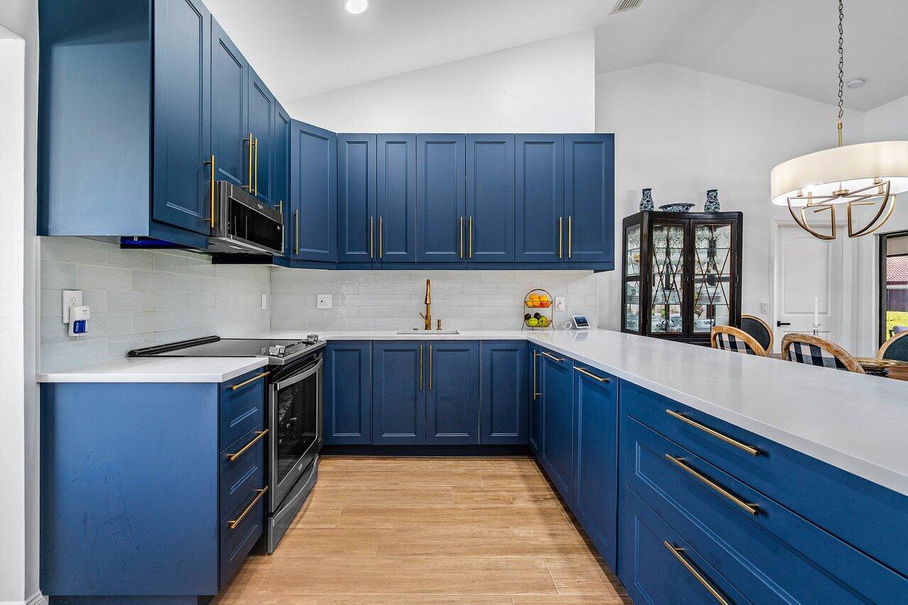 8195 Mooring Circle Boynton Beach, FL 33472 - Photo 8 of 28 a kitchen with stainless steel appliances granite countertop wooden cabinets a stove top oven a sink and dishwasher